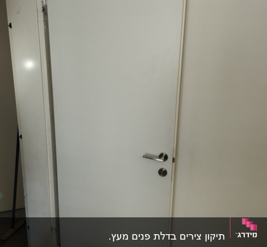דלת לבנה עם ידית מתכת כסופה
